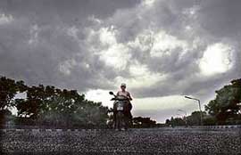 A girl rides her scooter in the backdrop of dark clouds in Ludhiana on Thursday.
