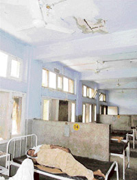 A patient lies in a ward of the civil hospital, Bathinda, below the area of the ceiling of which the plaster has peeled off.