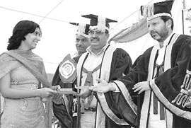 Shiv Raman Gour, Higher Education Commissioner, Haryana (centre) and Dr Arvind Sharma, MP, Karnal (right), presenting a trophy to a student at the DAV College convocation in Karnal on Sunday. 
