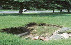 The inlet point of the dysfunctional underground rainstorm water drain is now an open 8-foot deep hole, dangerous and unmanned.