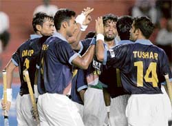 Dilip Tirkey (left) celebrates with team-mates after scoring a goal during the Pool B match against China.  AFP