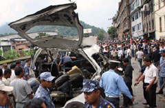 Nepalese policemen inspect the site of a blast, which struck commuters aboard a minibus on Sunday in Kathmandu.