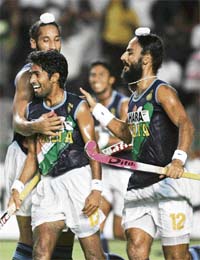 Shivendra Singh (C) celebrates his goal with teammates Rajpal Singh (R) and Sardara Singh during the first round match against South Korea
