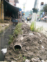 The unused pipe lies rusting in mud with a chocked drain by its side on Dharamsala Road at Kangra. 