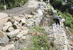 PWD labourers repair the Dharamsala-Khaniara road damaged in the recent floods
