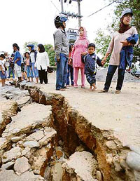 People stand near cracks on a road after an earthquake in the Indonesian city of Bengkulu on Thursday.