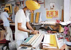 Workers busy making harmoniums at a workshop in Panipat