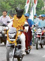 Magician O.P. Sharma drives a motorcycle after covering his head with a black cloth in the main market of Gurgaon