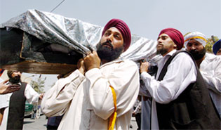 Afghan Sikhs shout slogans during a demonstration in Kabul on Monday as they carry a body prepared for cremation.