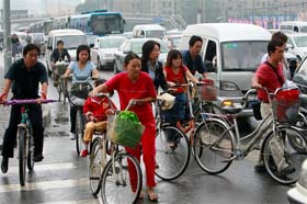 Chinese cyclists cross a busy street in central Beijing
