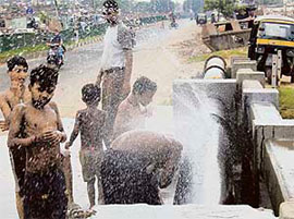Children bathe in water sprinkling from a burst pipe in Chandigarh.