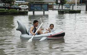 A man and his daughter row a boat on a flooded street after a powerful typhoon hit Wenling, east China's Zhejiang province