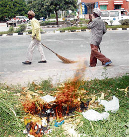 Safai karamcharis burn dry leaves and litter on the roadside near the mini secretariat in Karnal.