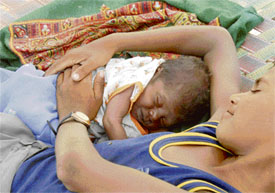 Big brother keeps a protective hand on his sibling as the child sleeps, safely ensconced in his care, at a roadside near Ambala.