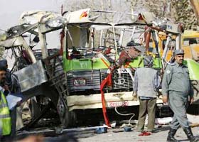 An Afghan policeman keeps watch next to the wreckage of a police bus after a suicide blast in Kabul
