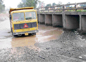 Vehicles are forced to use the riverbed after the Chikni Bridge was closed for repairs.