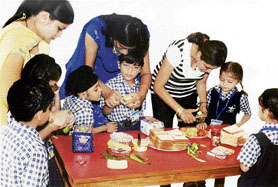 Teachers of Bal Bharti Public School give tips in sandwich-making to children in Ludhiana on Tuesday.