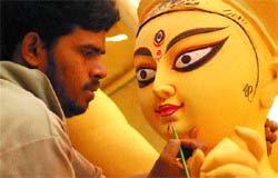 An artist gives finishing touches to an idol of Goddess Durga ahead of the Durga festival, at a workshop in Jhilmil in the Capital