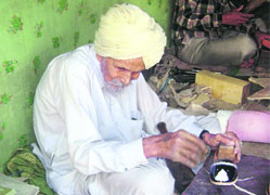 Eighty-year-old jutti maker Dalip Singh sits hunch-backed in Muktsar