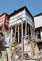 The rear view of a shop situated on The Mall Road shows wooden pillars supporting it. The structure poses a safety threat but no one seems to be bothered. 