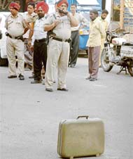 A policeman alerts the PCR about an unclaimed suitcase; and (right) opens it in Bhadaur House Market, Ludhiana