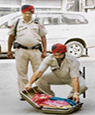 A policeman alerts the PCR about an unclaimed suitcase; and (right) opens it in Bhadaur House Market, Ludhiana