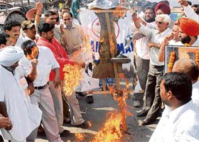 An activist of the National Integrated Forum of Artists and Activists (second from left) tries to save his face from flames during the burning of an effigy of the chairman of the UPSC in Karnal