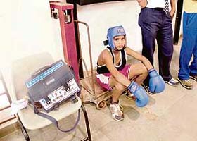 A participant at the Inter-School Boxing Tournament in Sector 42 sits on a weighing machine as he waits for his turn
