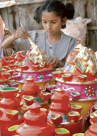 A little girl, who earns livelihood by selling earthenware, paints a picture of Lord Ganesha in Ludhiana on Thursday.