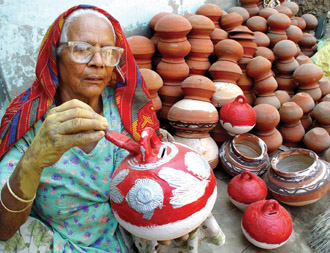 A woman painting red a coin bank, popular among kids, ahead of Diwali, the festival of lights, in Bathinda on Saturday. 