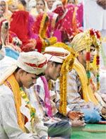 Bridegrooms and their brides (in the background) after a mass marriage ceremony in Maandi Pehowa village in Kurukshetra