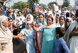 Women outside the Nangal police station demanding arrest of the money lender.