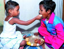 A sister offers sweet to her brother on the occasion of Bhai Dooj in the Capital on Sunday.