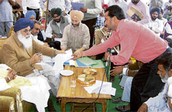 Chief Minister Parkash Singh Badal gives away a cheque to a punchiest member at Chandpur Asmani village
