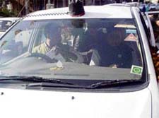 Former CM P.K. Dhumal sits in a car with red light atop after attending a party workers meet in Kangra district, (below) a ruling party leaders garlanded car during a rally in Kangra.
