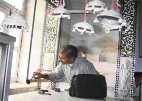 A forensic expert lifts fingerprints from the scene of theft of idols in Kaasan Pahadh village, Manesar