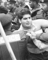Policemen arrest a supporter of cricketer-turned-politician Imran Khan during a demonstration in Lahore on Thursday, a day after Khan was arrested and later charged under anti-terror legislation.