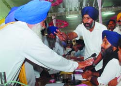 Acting president, SAD, Sukhbir Singh Badal (extreme right) attending to the problems of villagers in Kotkapura on Friday.