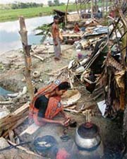 A Bangladeshi cyclone-affected woman prepares a meal on the site of her devastated house in Moralganj, on the south coast of Bangladesh