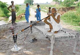 An old man takes a drag on his hookah in Budhanpur village of Panipat district