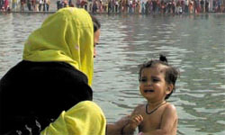 A woman gives bath to her child on the occasion of Gurpurb at the Gurdwara Bangla Sahib in the Capital on Saturday.