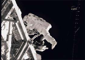 Flight engineer Dan Tani stows a storage bag on the exterior of the International Space Station during a spacewalk in this image from NASA TV