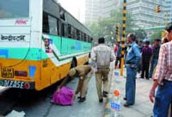 A policeman covers the body of a man who collapsed after being hit by a Blueline bus at Barakhambha Road in the Capital on Sunday. 