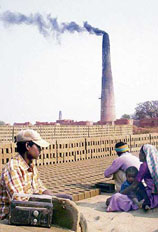 Unaware of the consequences of pollution, a mother holds her baby in lap while her husband makes bricks at a brick-kiln at Nala village near Gharota in Gurdaspur district.