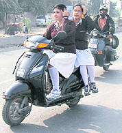 Schoolgirls drive a scooter without helmets in clear violation of the traffic rules in Ambala. 