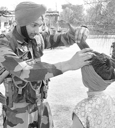 A jawan helps a child artiste to tie a turban during the Army fair, Virasat 2007, in Noshera, 150 km from Jammu, near the Line of Control, on Monday.