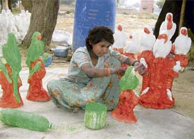 A young girl gives the finishing touches to toy birds in Hisar. Several such children ply their trade on pavements in the city