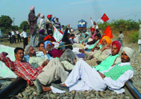 Members of Technical Services Union, BKU and other farmers organisations staging a dharna at a railway crossing near the thermal plant in Bathinda on Wednesday.