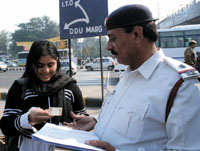 A traffic policeman chalans a girl for wrongly crossing a road at Tilak Brige red light in the Capital on Wednesday.