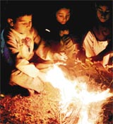 Street children sit around a fire as the temperature fell in Jammu on Monday.